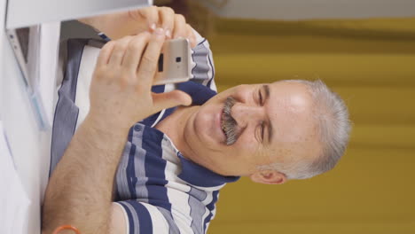 Vertical-video-of-Home-office-worker-old-man-texting.